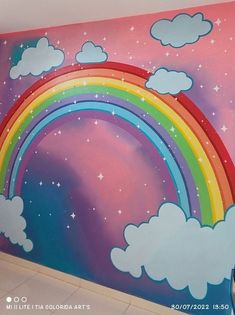 a rainbow painted on the side of a wall with clouds and stars above it,