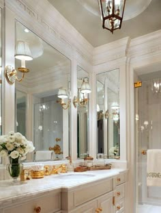 a white bathroom with gold accents and chandeliers