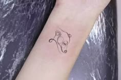 a small black and white dog tattoo on the left arm, it looks like an animal