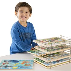 a young boy sitting at a table with a stack of books