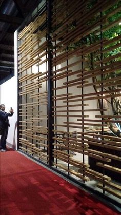 people are looking at wooden slats on the side of a building with red carpet