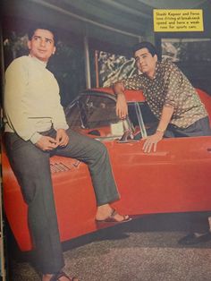 two men sitting on top of a red car