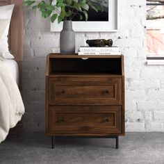 a bedroom with a bed, nightstand and plant on the end table next to it