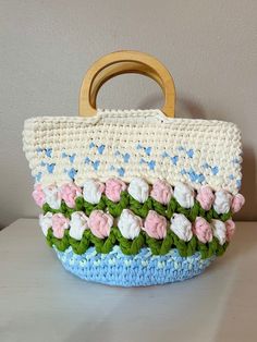 a crocheted purse with flowers and leaves on the handle is sitting on a table