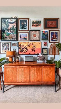 a living room filled with lots of pictures on the wall above a large wooden cabinet