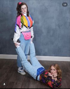 a woman is laying on the floor with her leg up and another person standing behind her