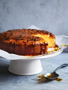 a cake sitting on top of a white cake plate next to a fork and spoon