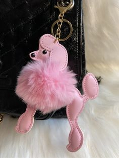 a pink poodle keychain hanging from a black purse