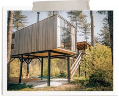 a small wooden structure in the middle of some trees and grass with stairs leading up to it