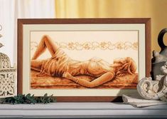 a cross stitch picture of a woman laying on the floor