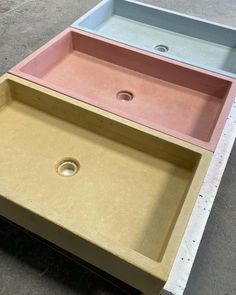 three different colored sinks sitting on top of each other in front of a wall and floor