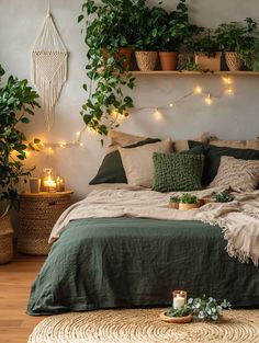 a bed covered in lots of pillows and blankets next to potted plants on the wall