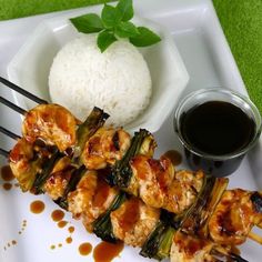 a white plate topped with chicken and veggies next to rice on a green mat