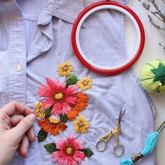 someone is working on an embroidered flower design with scissors and other crafting supplies nearby