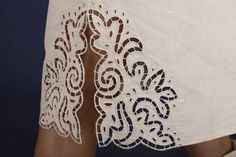 the back of a woman's white dress with an intricate lace design on it