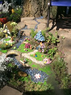 a miniature garden is shown in the shape of a fairy house and pond with flowers