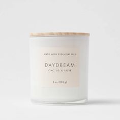 a white candle with a wooden lid that reads, daydream cactus & rose