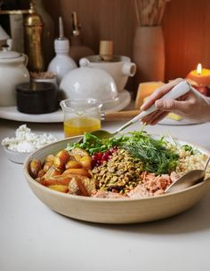 a person holding a knife over a bowl of food on a table with other dishes