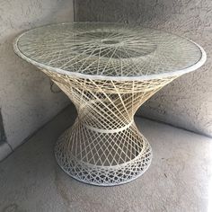 a glass table sitting on top of a cement floor next to a wall and window