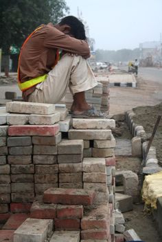 a man sitting on top of a pile of bricks