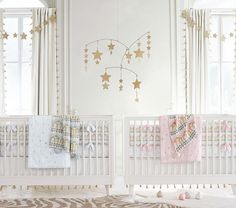 two white cribs with gold stars on them in a baby's room