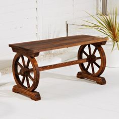 a wooden bench sitting on top of a white floor next to a potted plant