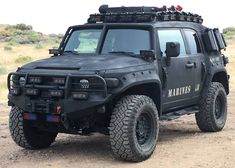 a black hummer truck parked in the desert with its lights on and four wheel drive