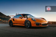 an orange porsche sports car parked on the road