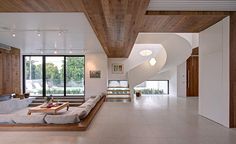 a living room filled with lots of furniture next to a large glass window on top of a wooden ceiling