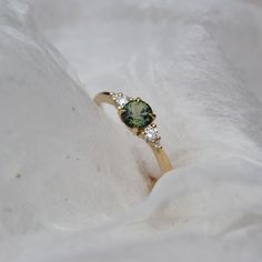 a close up of a ring with a green stone and diamonds on it's side