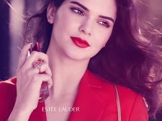 a woman with red lipstick holding a ring and looking at the camera while wearing a red dress