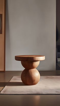 a round wooden table sitting on top of a white rug in front of a wall