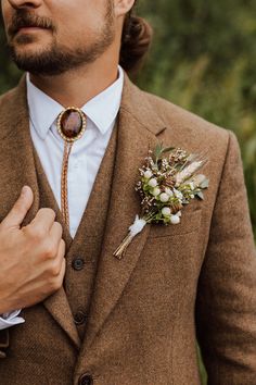 a man wearing a brown suit and flower boutonniere