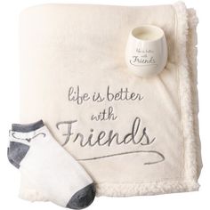 a white blanket with two socks and a mug on it that says, life is better with friends