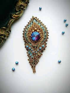 a blue brooch sitting on top of a table next to beads and a mirror