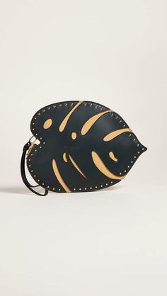 a black and gold fish shaped purse with studded details on the front, sitting on a white surface