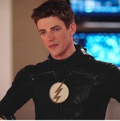 a young man in a black leather suit with a flash symbol on his chest and arm