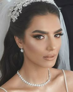 a woman wearing a bridal veil and tiara with pearls on the headband