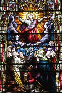 a stained glass window with the image of jesus surrounded by other people and angels on it