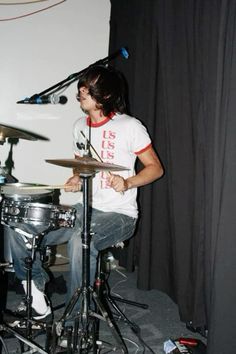 a young man playing drums in front of a microphone