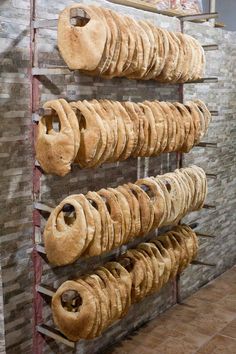 a rack filled with lots of doughnuts next to a brick wall