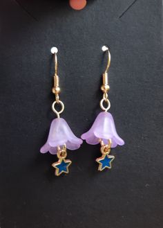 purple and blue earrings with stars hanging from them on top of a black countertop