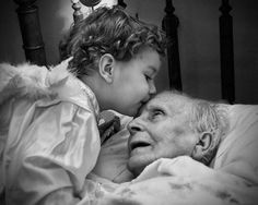 an older woman laying in bed next to a young boy who is kissing her face