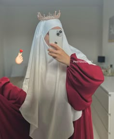 a woman in a red dress taking a selfie with her cell phone wearing a crown