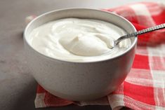 a bowl of yogurt sitting on top of a red and white checkered table cloth