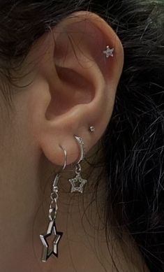 a close up of a person's ear with three stars dangling from the side