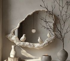 three birds perched on a tree branch in front of a mirror and vases with branches