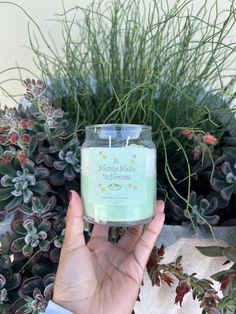 a person holding a candle in front of some plants