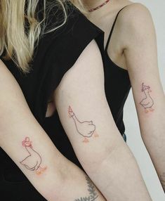 two women with matching tattoos on their arms, one holding the other's arm