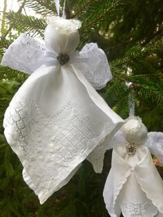 two white christmas bells hanging from a pine tree with lace on the top and bows at the bottom